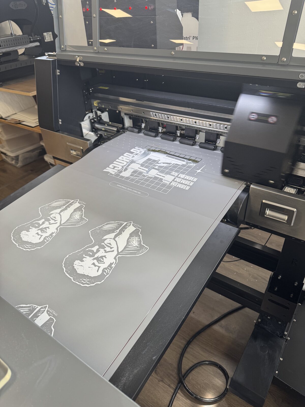 Großformat-DTF-Drucker druckt das weiße Houdini-Motiv auf Transferfolie für das Shirt des Secret Magic Store